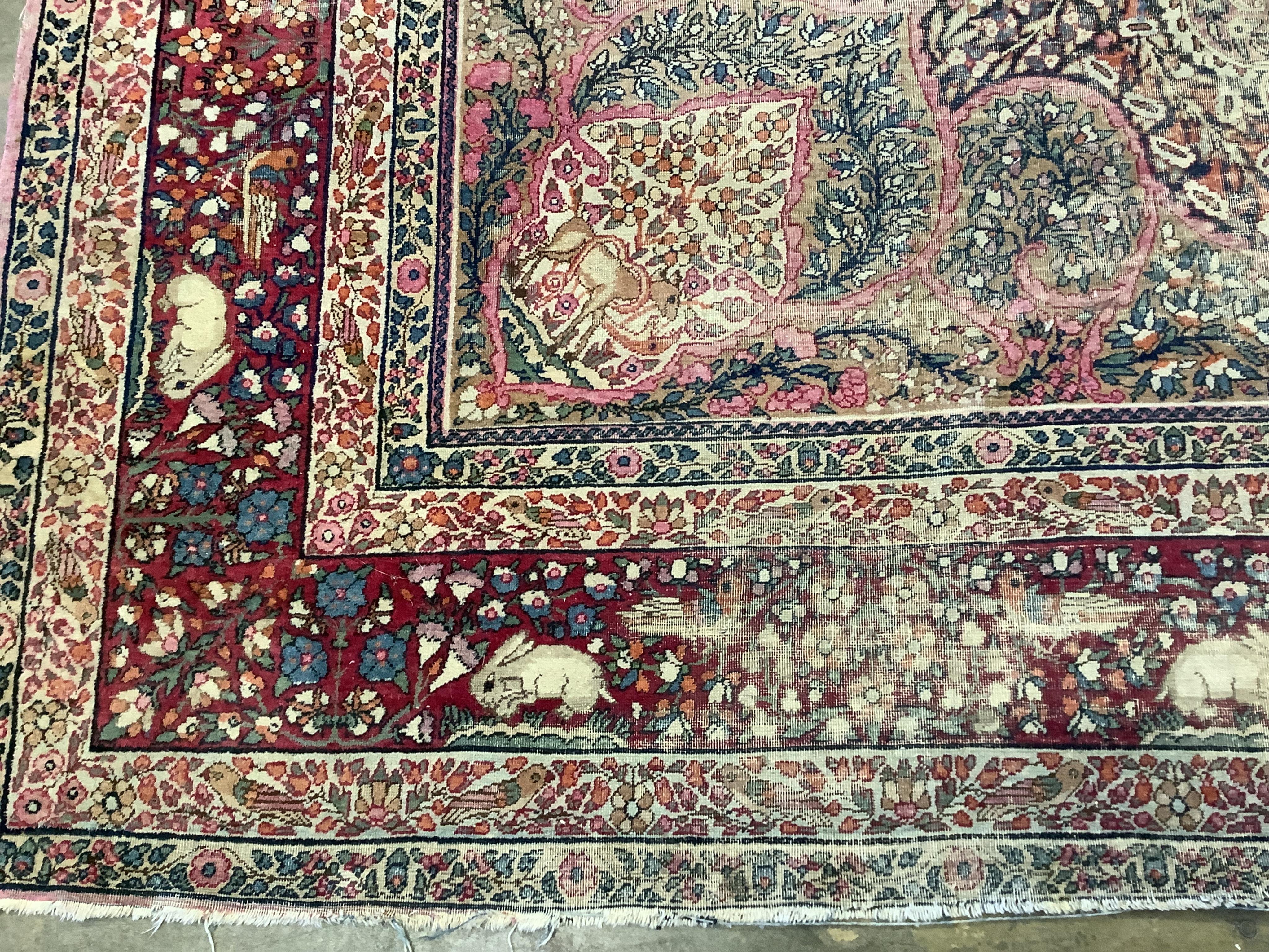 An antique Kirman ivory ground pictorial carpet (severely worn), 348 x 265cm